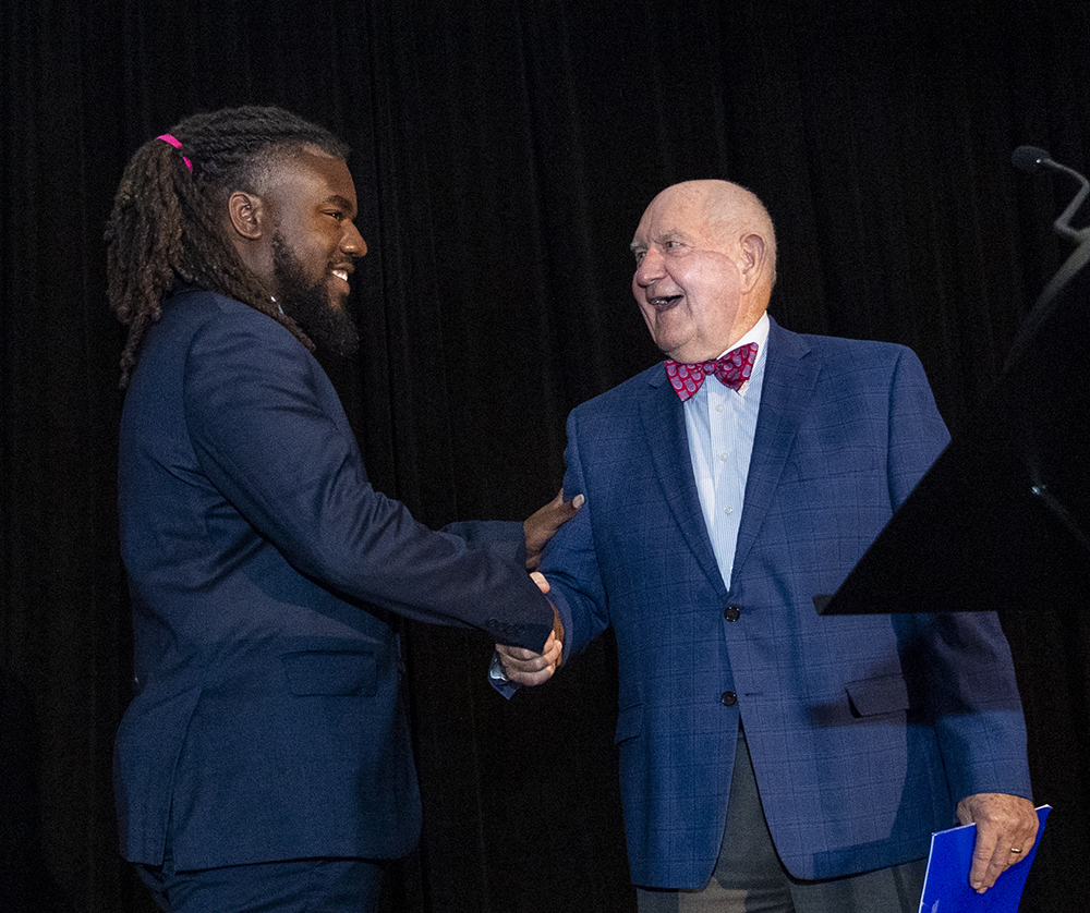 Mills, left, is greeted onstage by USG Chancellor Sonny Perdue.